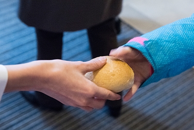 eine Hand reicht einer anderen Hand ein Brötchen