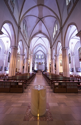 Blick durch den Mittelgang der violett beleuchteten St. Agatha-Kirche in Richtung Altar