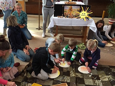 Kinder knien auf einer Decke hinter dem Altar der St. Maria Himmelfahrt Kirche und basteln. Kinder knien auf einer Decke hinter dem Altar der St. Maria Himmelfahrt Kirche und basteln.