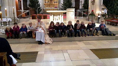 Pastor Timo Holtmann sitzt zusammen mit den Kindern auf dem Stufen vor dem Altar. Sie singen ein Lied. Pastor Timo Holtmann sitzt zusammen mit den Kindern auf dem Stufen vor dem Altar. Sie singen ein Lied.