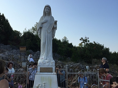 Erscheinungsberg / der Podbrdo Er wird als der Ort der ersten Erscheinungen der Muttergottes betrachtet. Die Statue der Maria Königin des Friedens erreicht man über einen steilen Pfad, der von unzähligen Pilgern täglich begangen wird. Viele sind in tiefer Betrachtung und Stille versunken oder singen Lieder. An der Stelle, an der die Muttergottes erschienen ist, wurde am 8. September 2001 eine Statue errichtet. Erscheinungsberg / der Podbrdo Er wird als der Ort der ersten Erscheinungen der Muttergottes betrachtet. Die Statue der Maria Königin des Friedens erreicht man über einen steilen Pfad, der von unzähligen Pilgern täglich begangen wird. Viele sind in tiefer Betrachtung und Stille versunken oder singen Lieder. An der Stelle, an der die Muttergottes erschienen ist, wurde am 8. September 2001 eine Statue errichtet.
