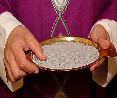 Der Priester hält eine Schale mit Asche Der Priester hält eine Schale mit Asche