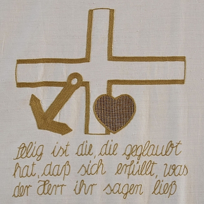 Gesticktes Bild im Hungertuch: Glaube (Kreuz), Hoffnung (Anker) und Liebe (Herz), die drei Grundtugenden des christlichen Glaubens zeigt dieses Bild. 