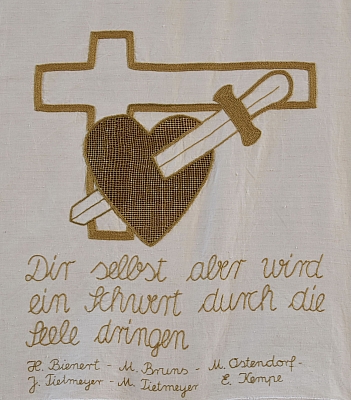 Gesticktes Bild im Hungertuch: Ein Herz wird von einem Schwert durchstoßen. Im Hintergrund ein Kreuz. Darunter ein Bibelvers und die Namen der Stickerinnen.