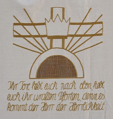 Gesticktes Bild im Hungertuch: Ein Tor, darüber Strahlen und eine Krone, dahinter das Kreuz.