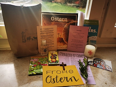 Inhalt der Ostertüte: Palmzweig, Osterheft, Kerze, Osterbild, Blumensamen, Kreuz, gelbes Schild mit der Aufschrift: FROHE OSTERN