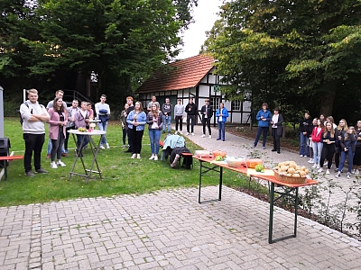 Jugendleiter und Jugendleiterinnen stehen auf dem Platz hinter dem Pfarrheim. Im Vordergrund ein Tisch mit Salaten und Brötchen.