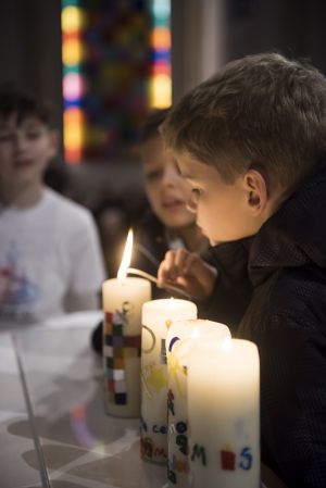 Kommunionkinder zünden ihre Gruppenkerze auf dem Altar an