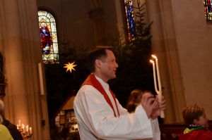 Pastor Timo Holtmann trägt brennende Kerze