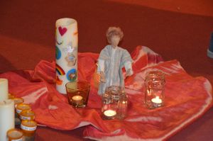 Eglifigur mit Kerzen auf einem roten Seidentuch